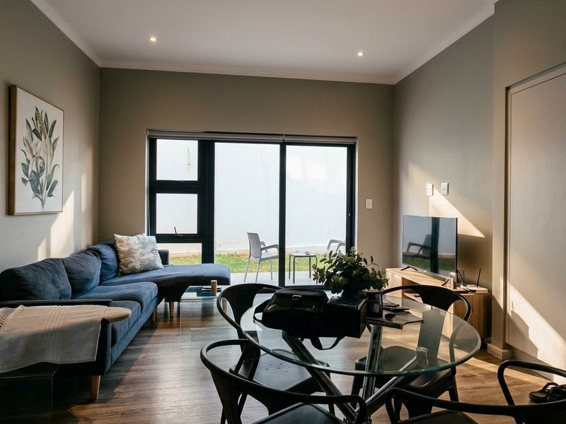 A modern open-plan living and dining area featuring laminate flooring, recessed lighting, and large sliding glass doors providing access to the outdoor space.