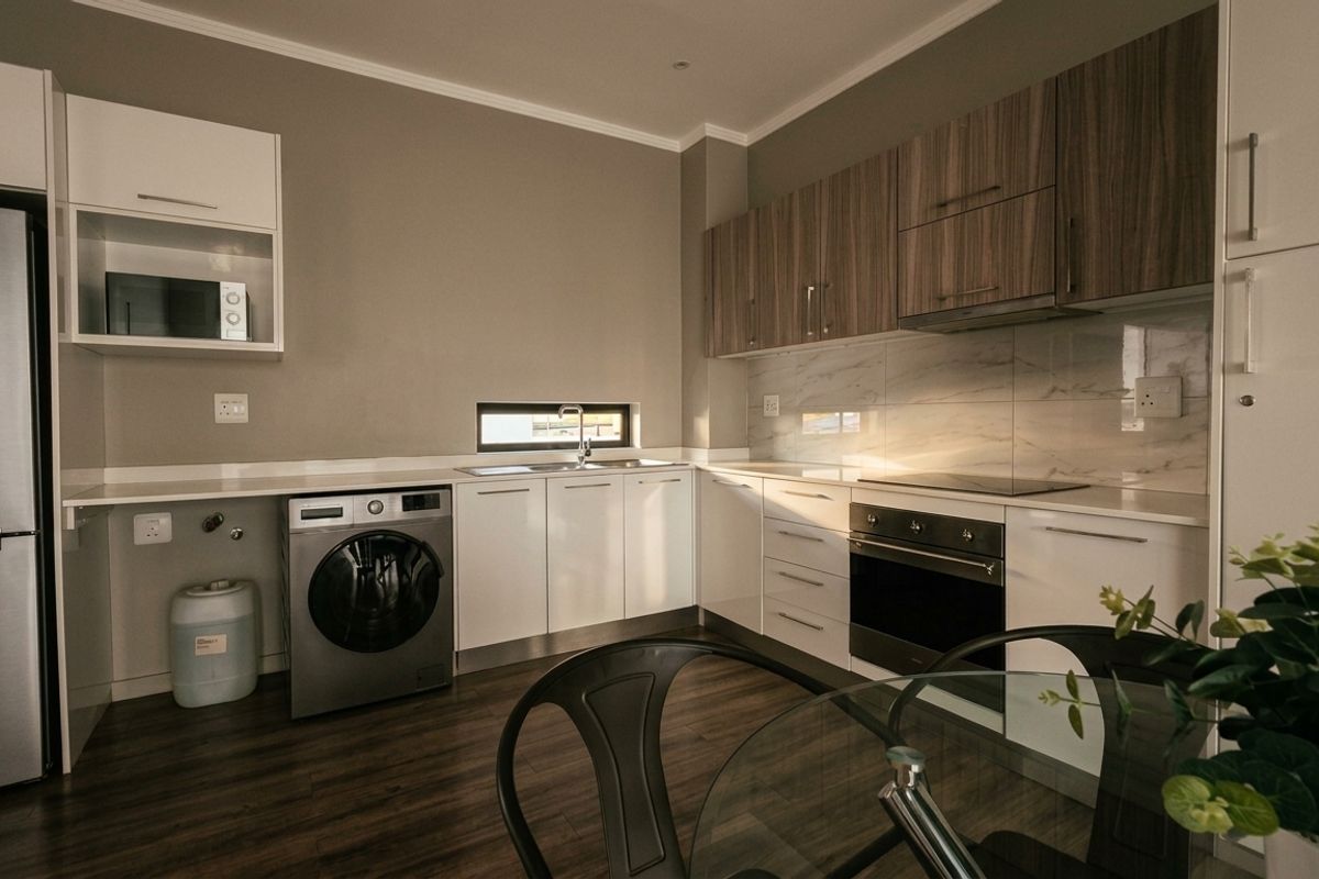 Modern kitchen featuring sleek white and wood-grain cabinetry, integrated appliances, marble-look splashback, and durable laminate flooring in a clean, contemporary layout.