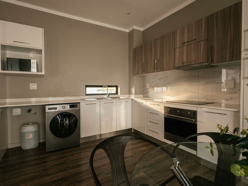 Modern kitchen featuring sleek white and wood-grain cabinetry, integrated appliances, marble-look splashback, and durable laminate flooring in a clean, contemporary layout.