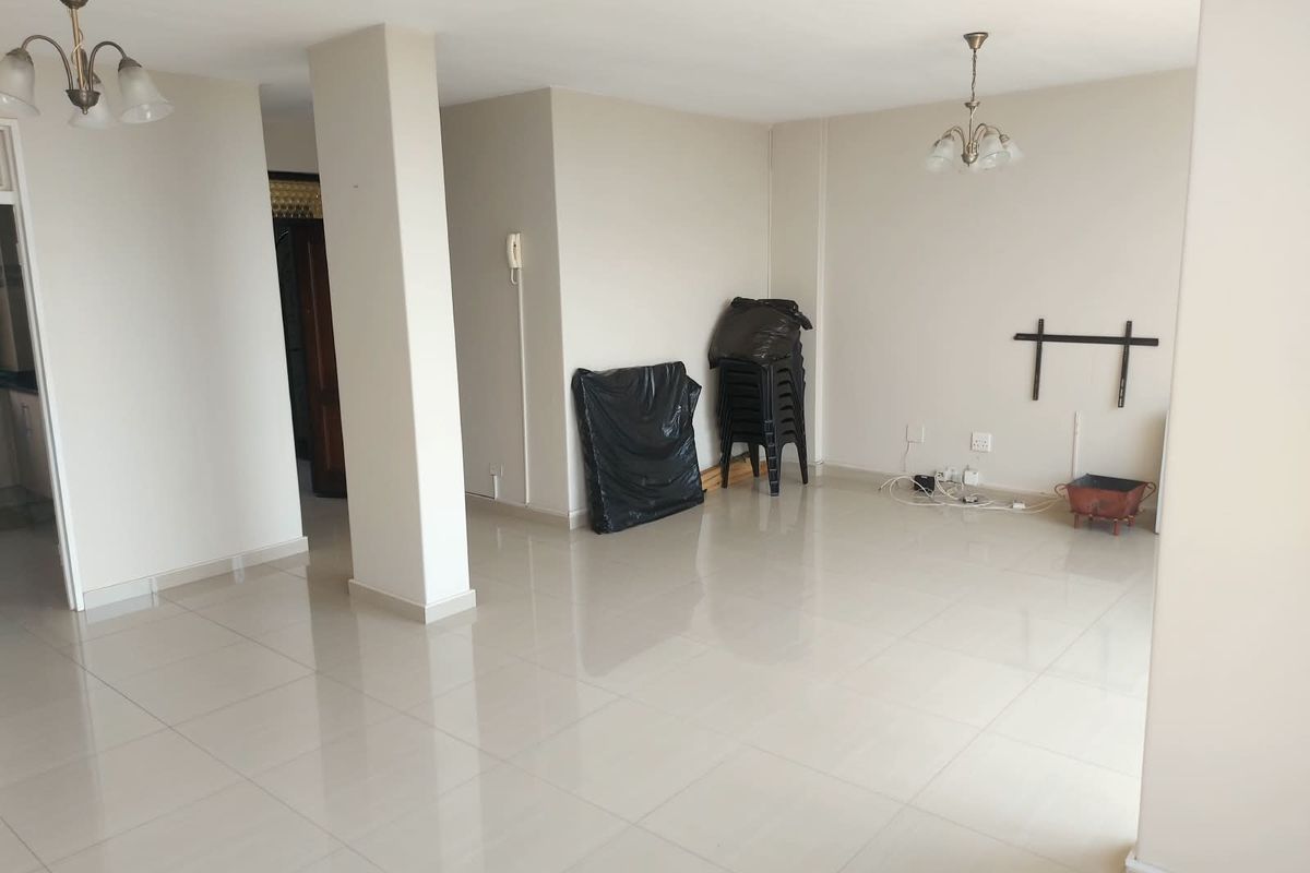 A spacious, neutral-toned living area featuring polished tile flooring, ceiling light fixtures, and an intercom system, offering a clean and versatile blank canvas.
