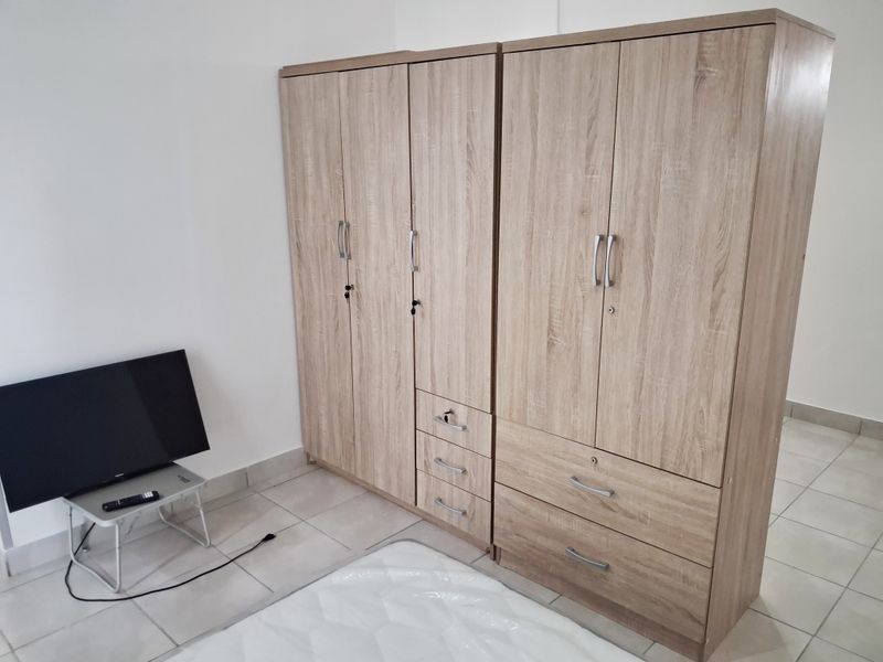 A bedroom featuring light-toned tiled flooring and neutral walls, providing a clean and functional space.