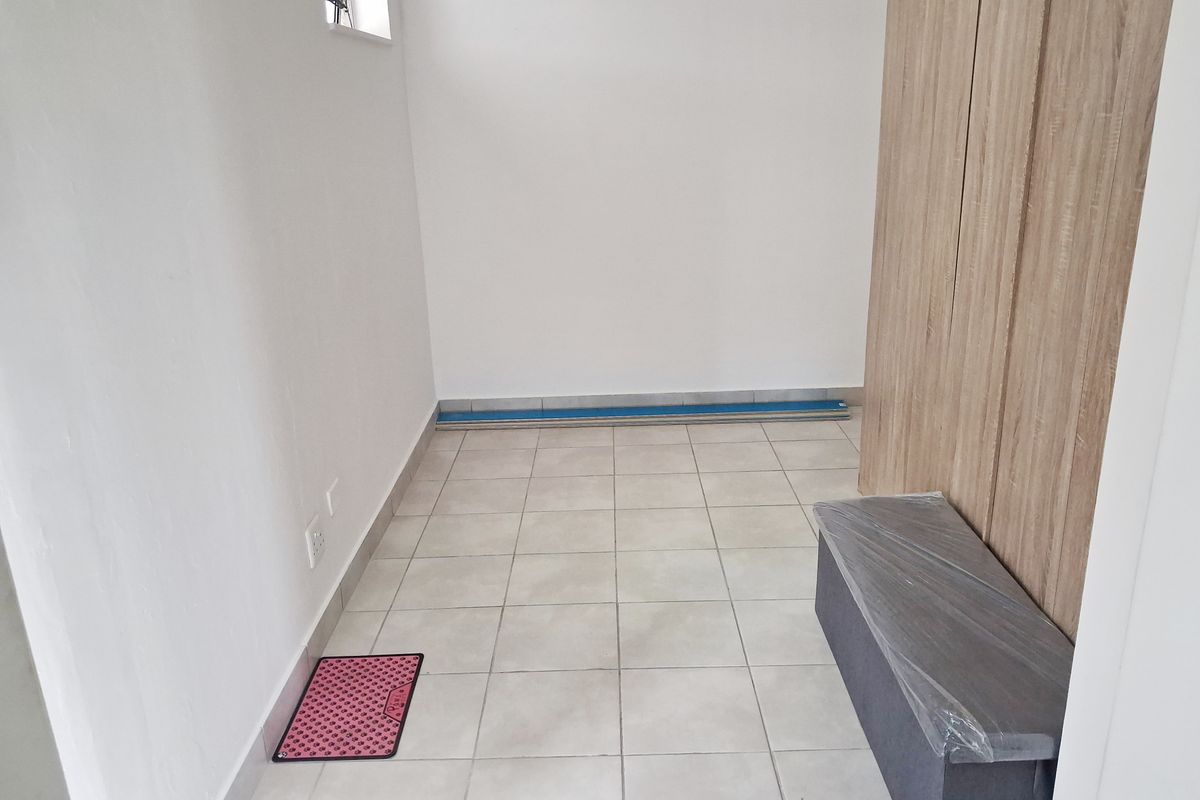 A clean, empty bedroom featuring neutral tiled flooring and modern built-in cupboards, offering a blank canvas for personalization.