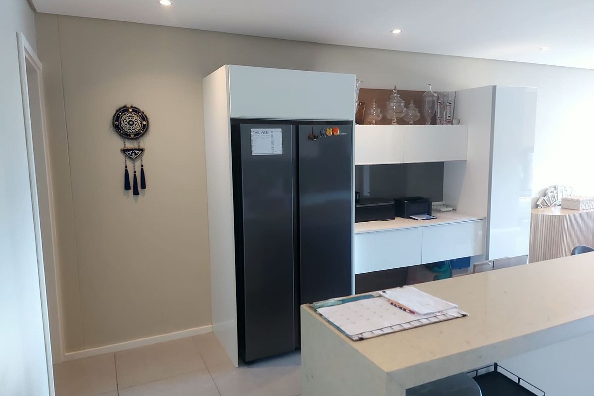 Modern kitchen area featuring sleek white built-in cabinetry, stone countertops, and recessed downlighting, offering a clean and contemporary aesthetic.