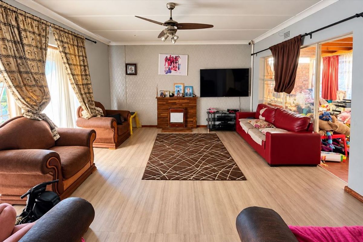 Spacious living room featuring laminate flooring, a ceiling fan, and a built-in fireplace, with direct access to an adjacent enclosed patio area.