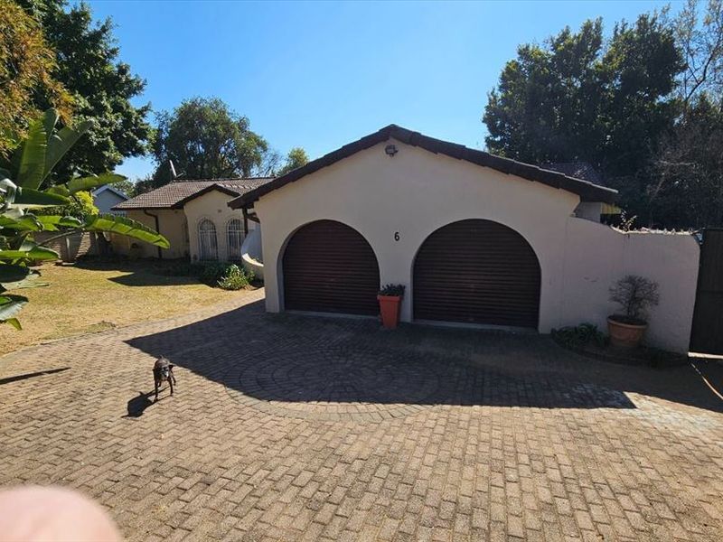 Front view of the property featuring a double garage with arched openings and a paved driveway.