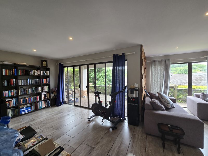 Spacious living area featuring large sliding glass doors that open to an outdoor deck, tiled flooring, and modern recessed lighting.
