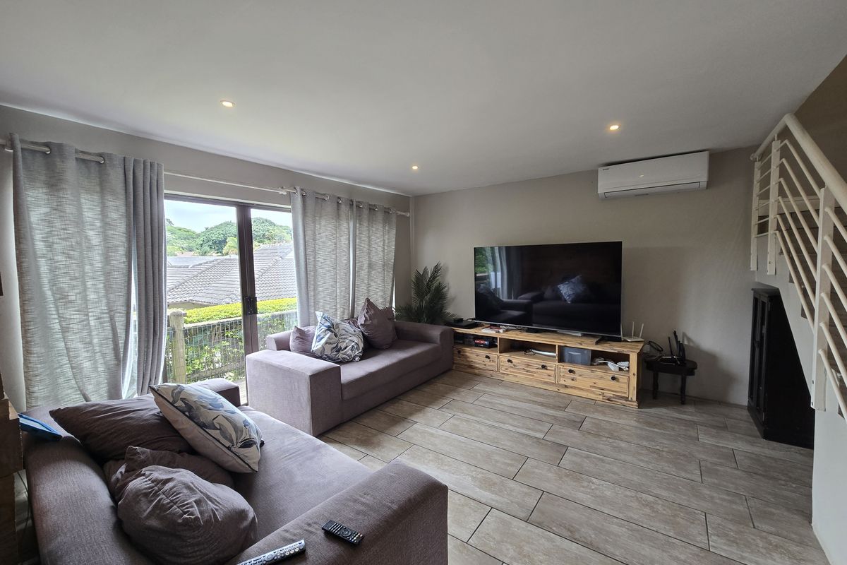 A comfortable living room featuring tiled flooring, recessed lighting, a split-system air conditioner, and direct access to an outdoor area via sliding glass doors.