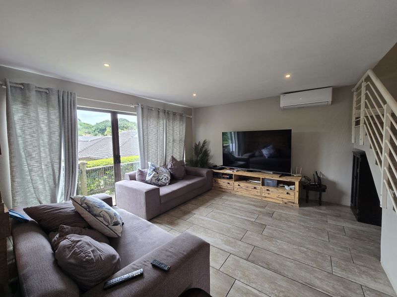 A comfortable living room featuring tiled flooring, recessed lighting, a split-system air conditioner, and direct access to an outdoor area via sliding glass doors.