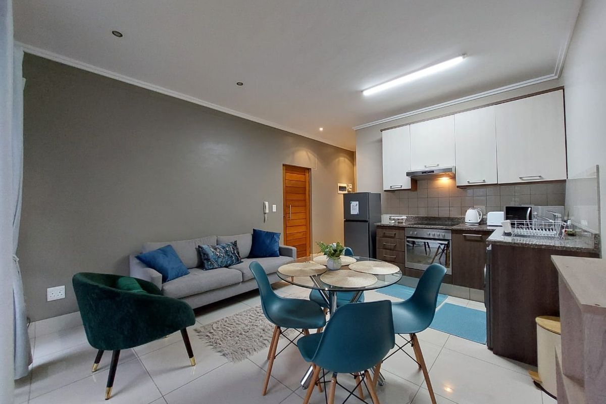 Modern open-plan living area featuring a well-appointed kitchen with granite countertops, built-in oven, extractor fan, and sleek tiled flooring throughout.