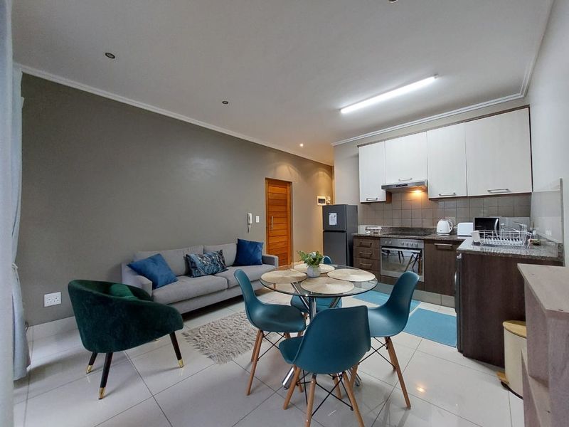 Modern open-plan living area featuring a well-appointed kitchen with granite countertops, built-in oven, extractor fan, and sleek tiled flooring throughout.