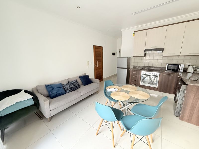 Open-plan living and kitchen area featuring modern cabinetry, granite countertops, integrated oven, and tiled flooring, creating a functional and cohesive living space.
