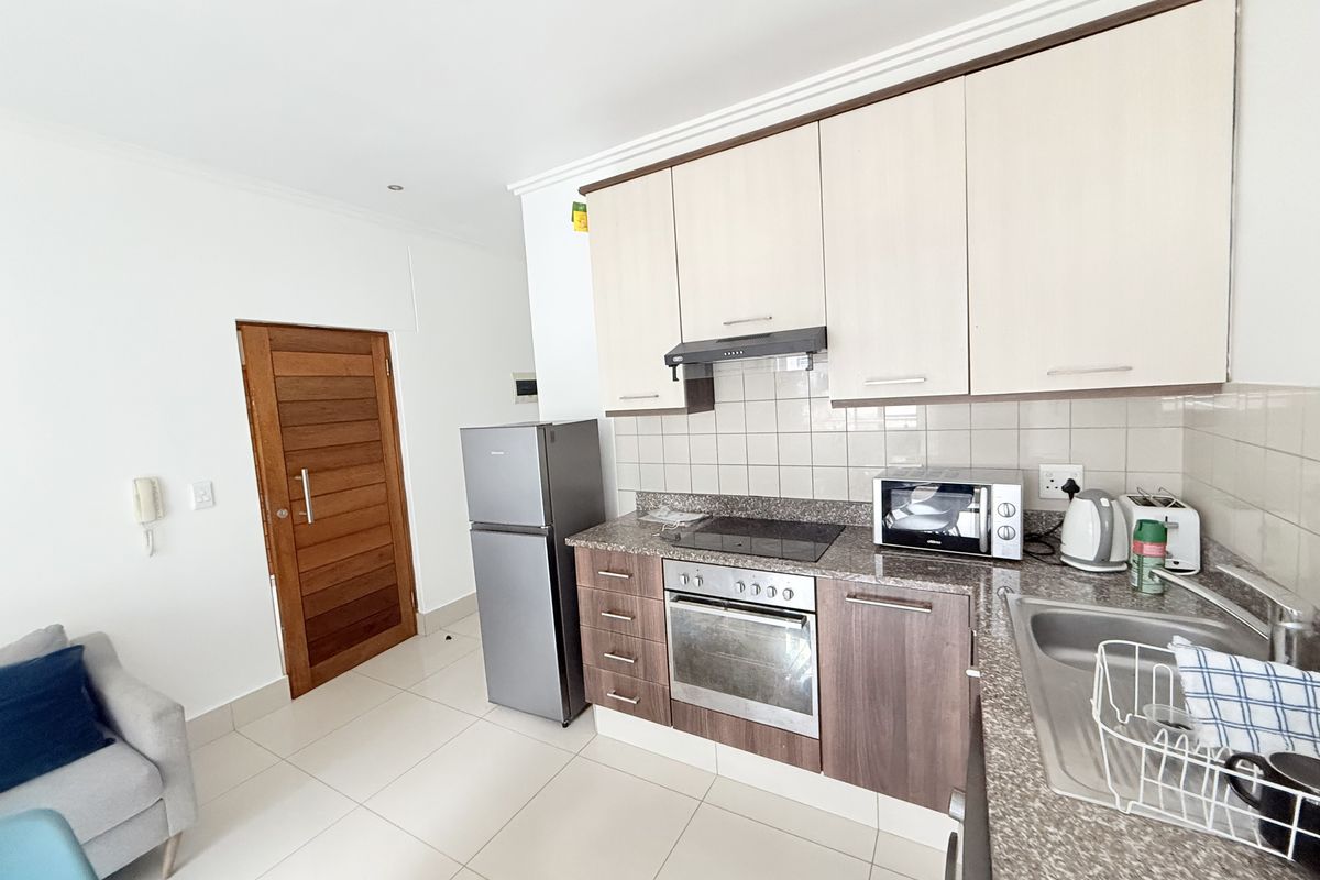 A functional kitchen featuring granite countertops, built-in cabinetry, a tiled backsplash, and integrated appliances including an oven and hob.