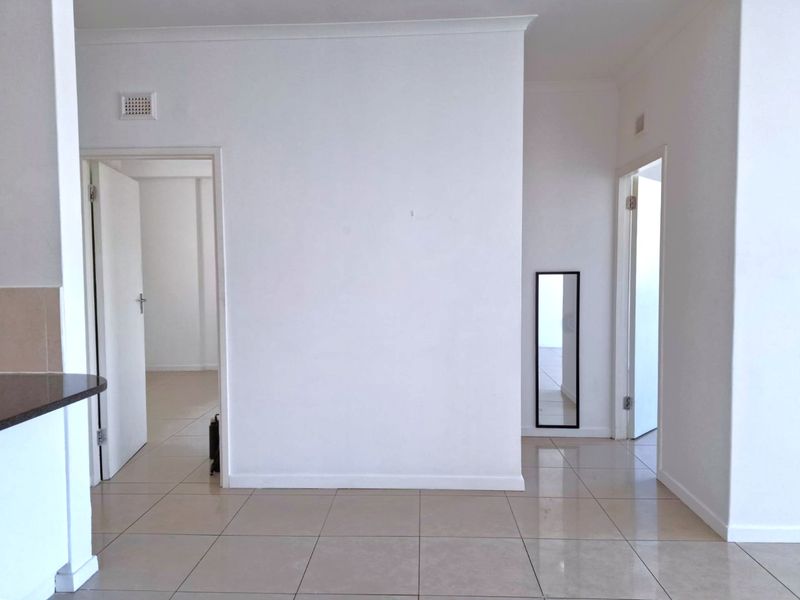 A bright and spacious hallway featuring neutral tiled flooring and clean white walls, providing access to multiple rooms within the apartment.