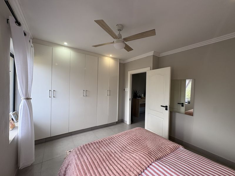 A well-maintained bedroom featuring built-in cupboards, tiled flooring, a ceiling fan, and recessed lighting, offering a clean and functional living space.