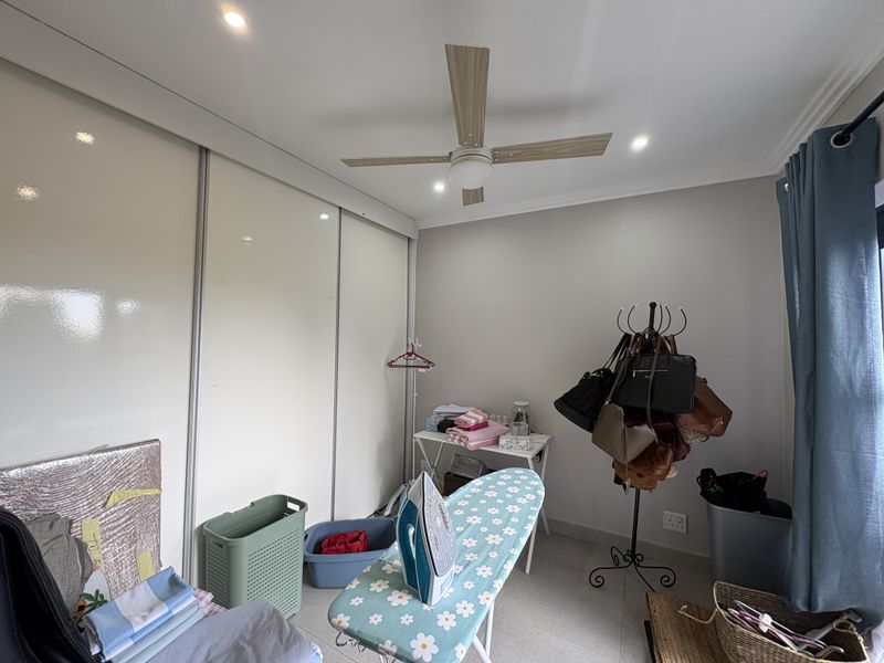 A functional bedroom featuring a large built-in sliding door wardrobe, ceiling fan, and recessed lighting, providing ample storage and comfortable climate control.