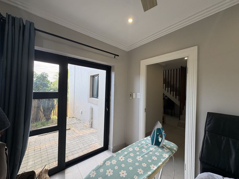A functional utility space featuring tiled flooring, recessed lighting, and a sliding door providing direct access to the paved outdoor area.