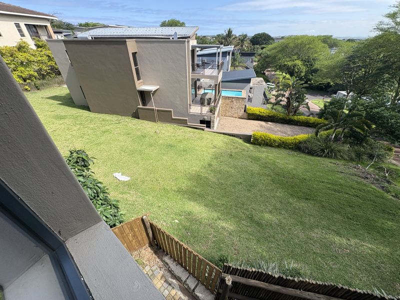 Elevated aerial view of the property grounds, featuring a spacious lawn, paved driveway, and a swimming pool area.
