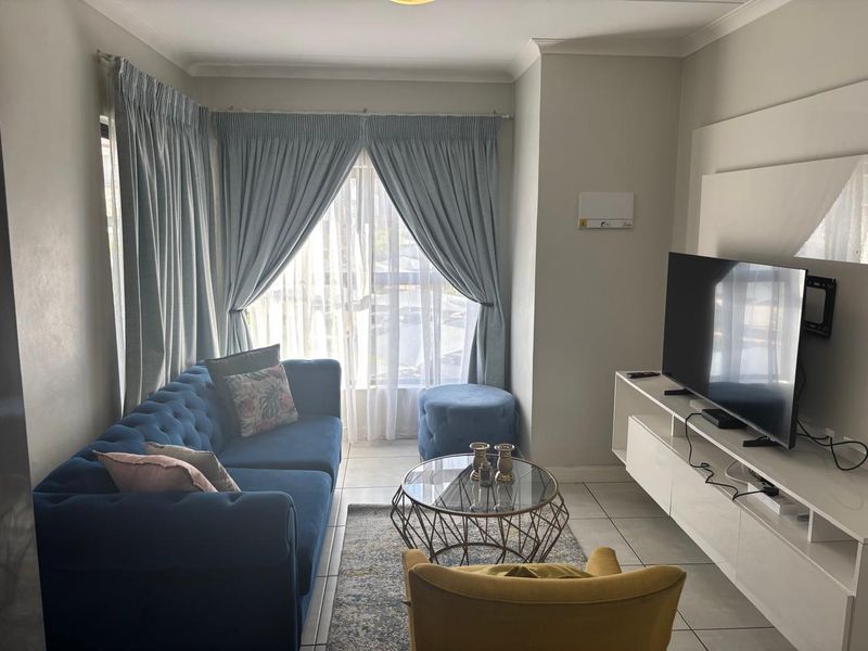 A well-maintained living room featuring tiled flooring, coved ceilings, and a built-in media console, offering a comfortable and functional space.