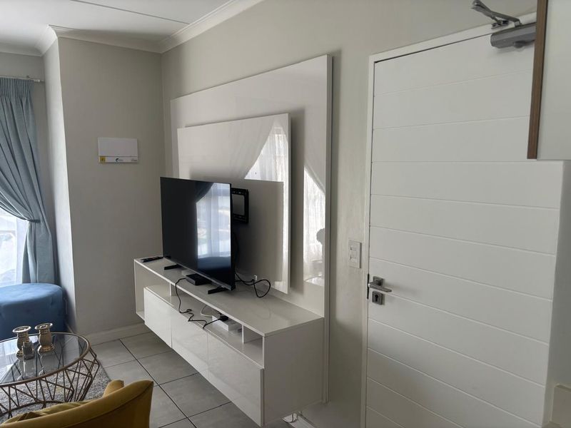 A well-maintained living room featuring a modern built-in media console, tiled flooring, and clean neutral wall finishes.