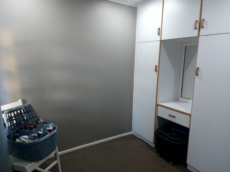 A bedroom featuring built-in cupboards with an integrated vanity mirror and drawer, providing ample storage space.