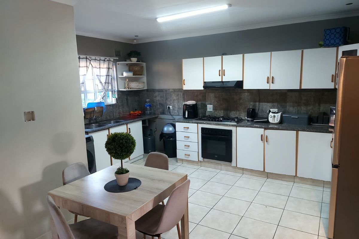 A functional kitchen featuring white cabinetry, a gas hob with extractor, built-in oven, and tiled flooring, offering a practical layout for daily cooking.