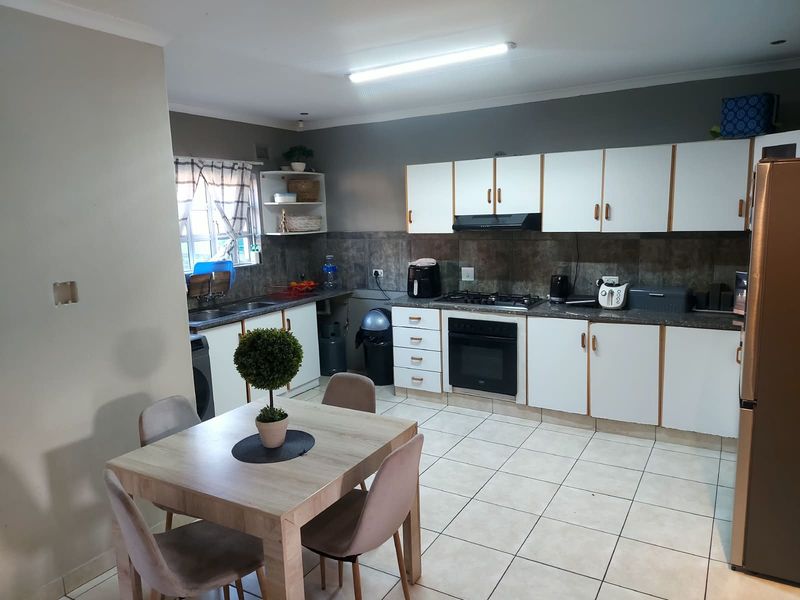 A functional kitchen featuring white cabinetry, a gas hob with extractor, built-in oven, and tiled flooring, offering a practical layout for daily cooking.