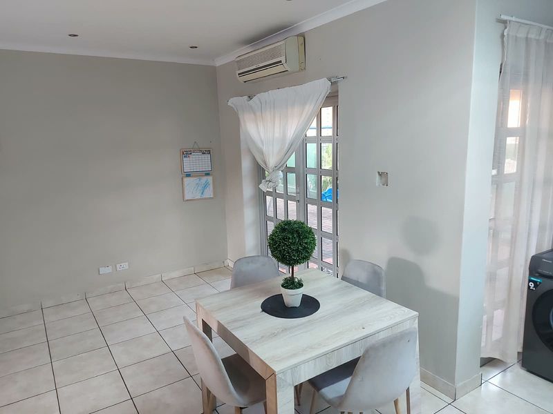 A functional living area featuring tiled flooring, recessed lighting, and an integrated air conditioning unit with direct access to an outdoor space.