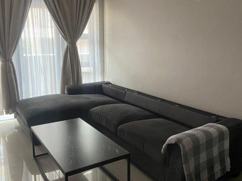 A comfortable living room featuring tiled flooring and a wall-mounted split-system air conditioner, providing a functional and well-maintained space.