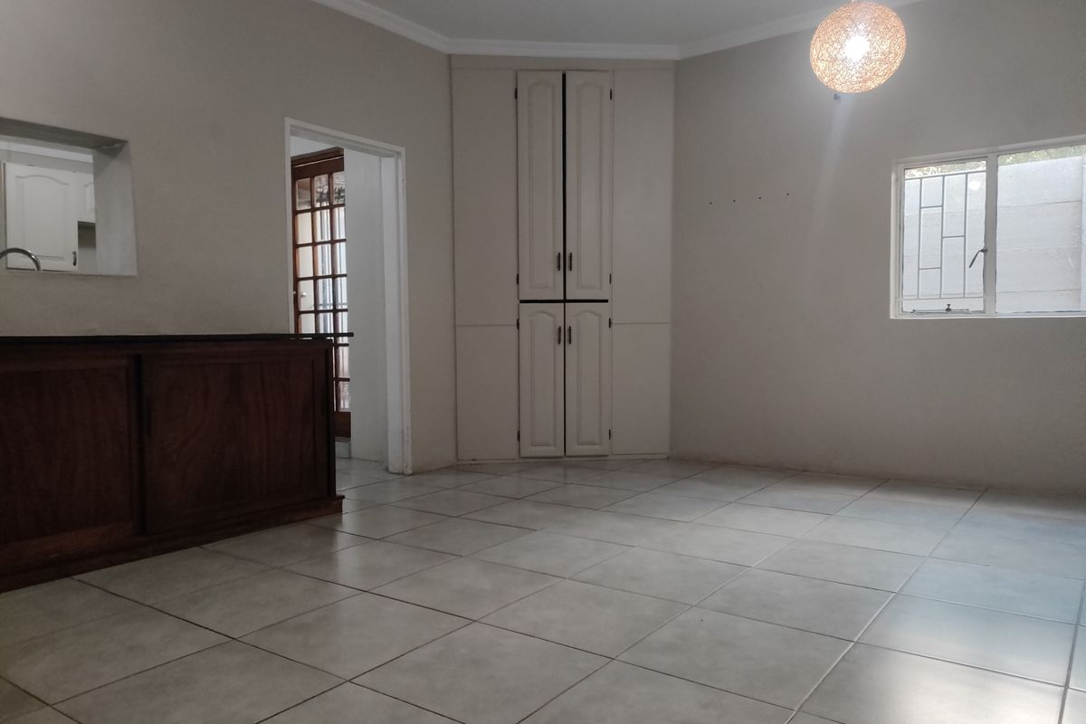 Spacious living area featuring neutral tiled flooring, built-in corner storage cabinetry, and a convenient serving counter connecting to the kitchen space.