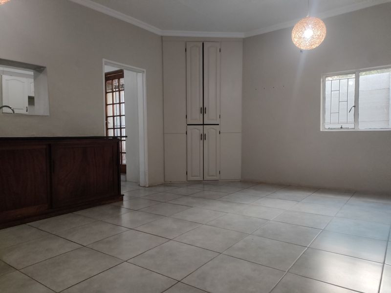 Spacious living area featuring neutral tiled flooring, built-in corner storage cabinetry, and a convenient serving counter connecting to the kitchen space.