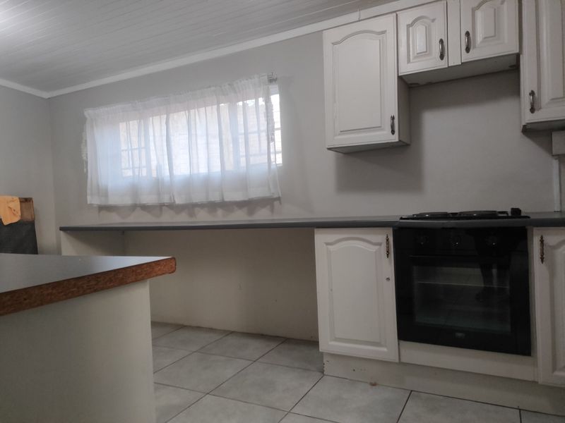 A functional kitchen featuring white cabinetry, a built-in oven and hob, tiled flooring, and a tongue and groove ceiling.