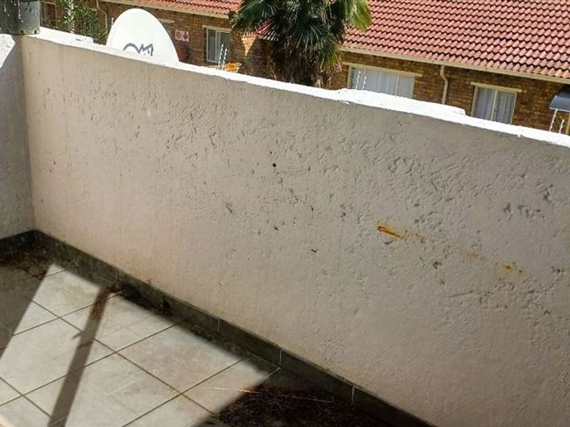 An outdoor balcony area featuring tiled flooring and a masonry balustrade, requiring maintenance and cleaning to improve its overall appearance.