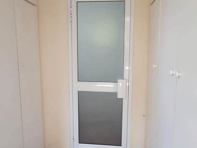 A functional entryway featuring extensive built-in storage cupboards and a modern frosted glass door, providing a clean and organized transition space.