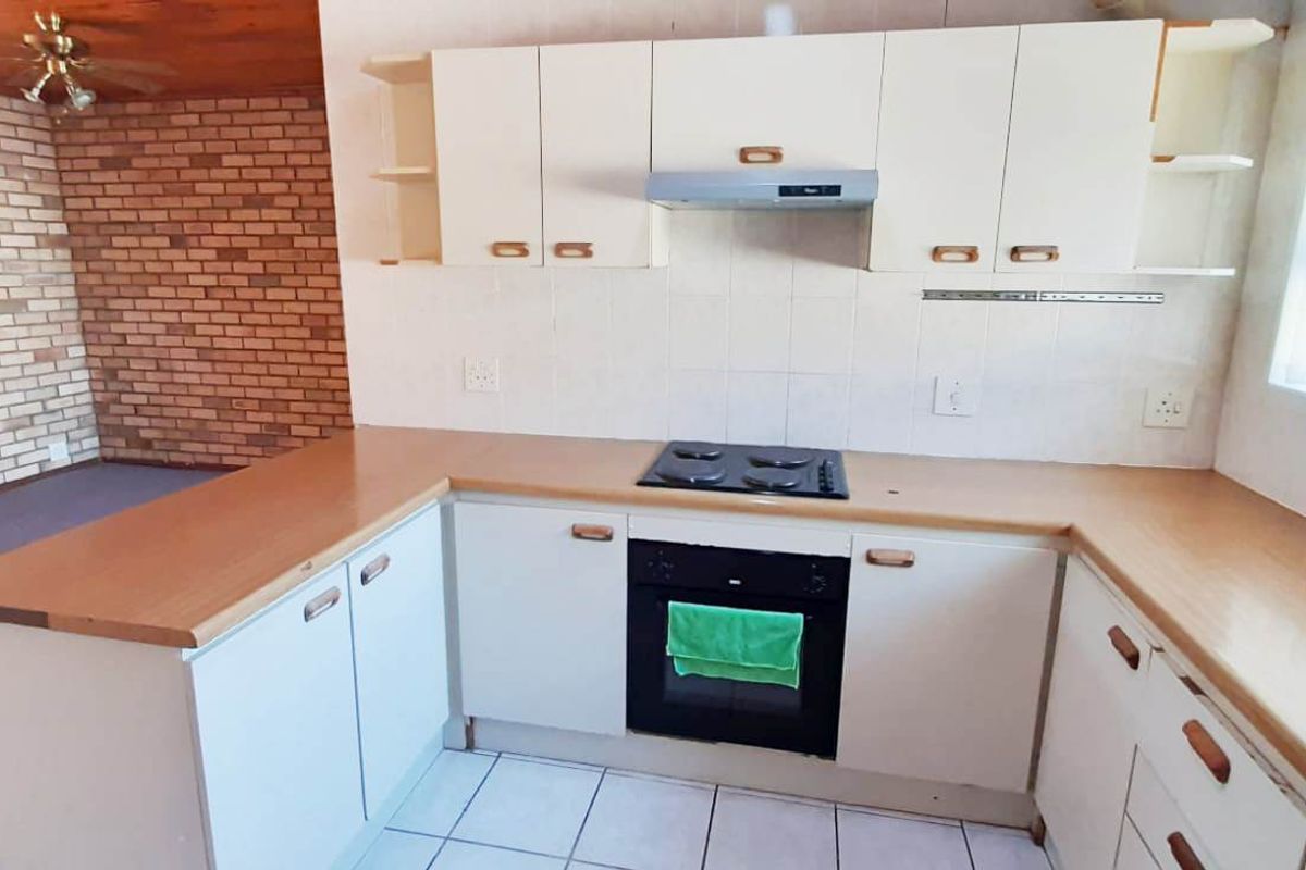 A functional kitchen featuring built-in cabinetry, laminate countertops, an electric hob, and an integrated oven, offering a practical layout for daily meal preparation.
