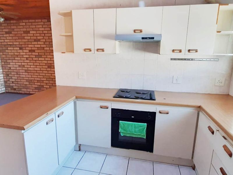 A functional kitchen featuring built-in cabinetry, laminate countertops, an electric hob, and an integrated oven, offering a practical layout for daily meal preparation.