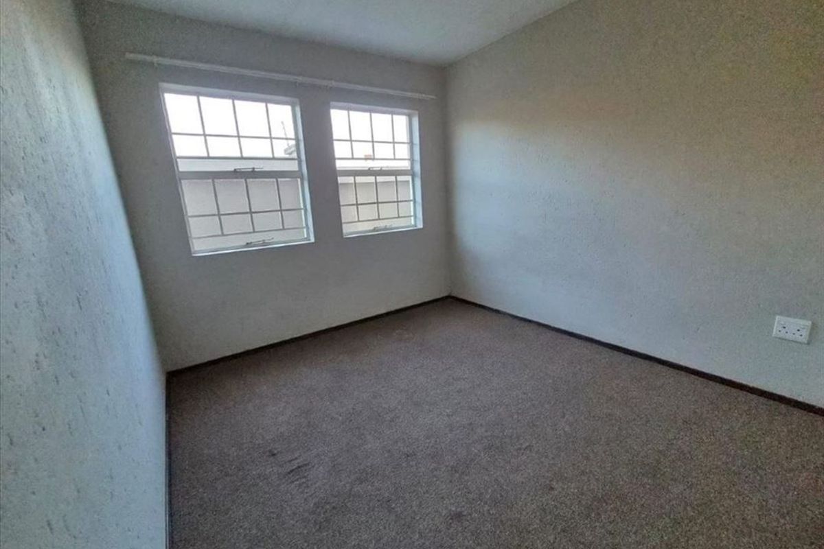 An empty bedroom featuring carpeted flooring and dual windows, providing a blank canvas for personalization.