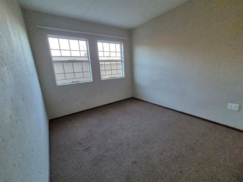 An empty bedroom featuring carpeted flooring and dual windows, providing a blank canvas for personalization.