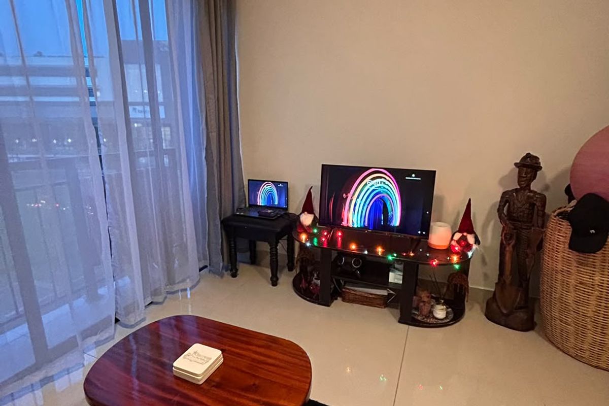 A living room area featuring large sliding glass doors leading to a balcony and neutral tiled flooring throughout.