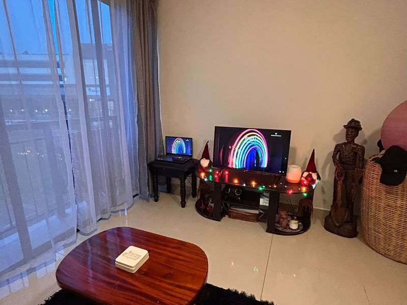 A living room area featuring large sliding glass doors leading to a balcony and neutral tiled flooring throughout.