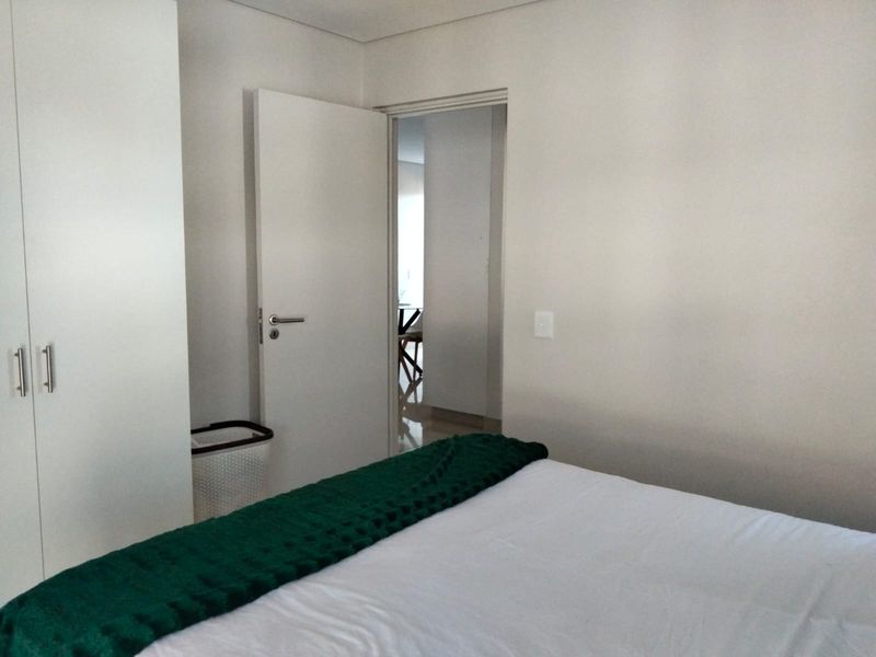 A clean and neutral bedroom featuring a built-in wardrobe and direct access to the adjacent living area.