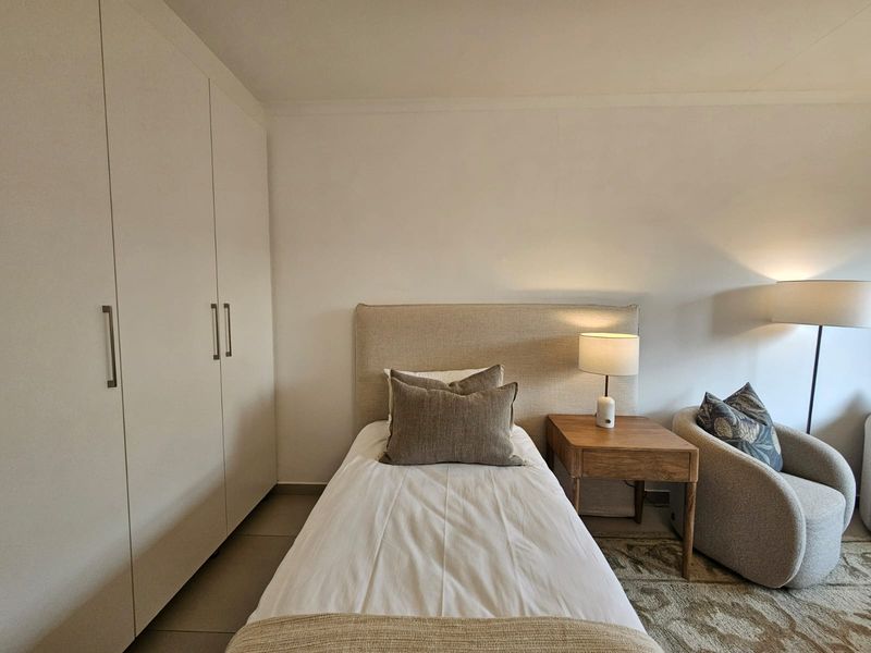 A well-maintained bedroom featuring neutral tones, tiled flooring, and ample built-in wardrobe storage.