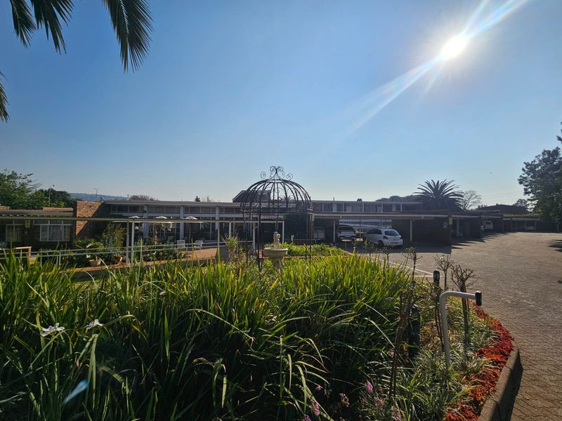 Front exterior view of the retirement village featuring a paved driveway, covered walkways, and well-maintained landscaped garden areas.
