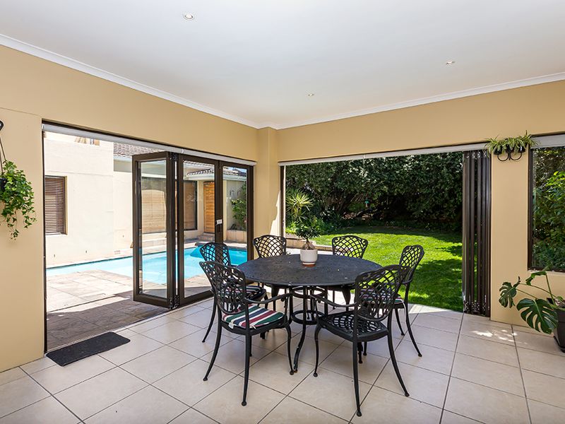 Covered patio area featuring tiled flooring and large stacking doors that provide seamless access to the garden and swimming pool.
