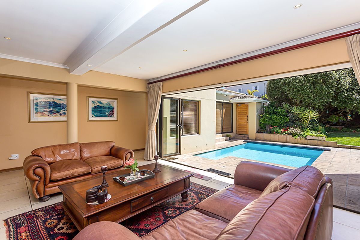 Spacious living room featuring large sliding glass doors that open directly onto a private swimming pool and garden area.