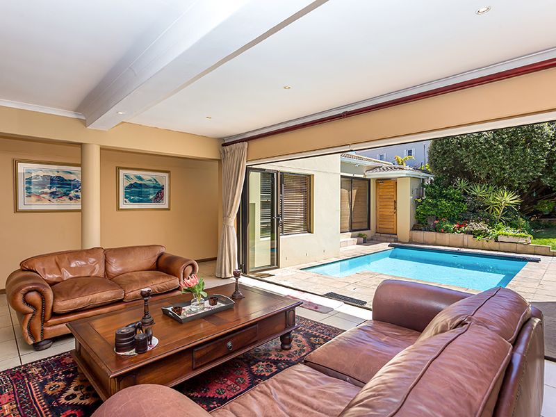 Spacious living room featuring large sliding glass doors that open directly onto a private swimming pool and garden area.