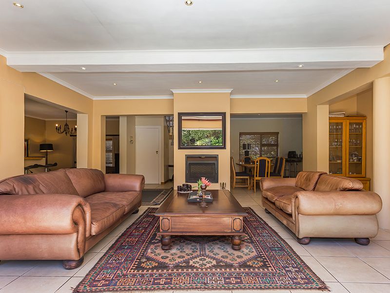 Spacious living room featuring a central built-in fireplace, tiled flooring, and recessed ceiling lighting, with an open-plan layout connecting to adjacent dining areas.