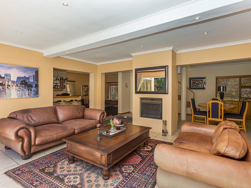 Spacious open-plan living area featuring a built-in fireplace, tiled flooring, and a dedicated bar section, offering a versatile layout for family living and entertaining.