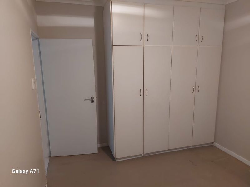 A clean, empty bedroom featuring ample built-in cupboard storage and neutral wall finishes, providing a blank canvas for personalization.