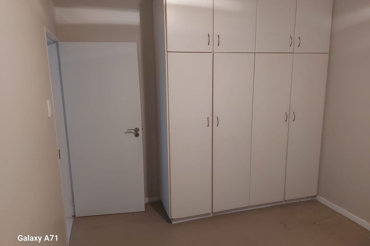 A clean, empty bedroom featuring ample built-in cupboard storage and neutral wall finishes, providing a blank canvas for personalization.