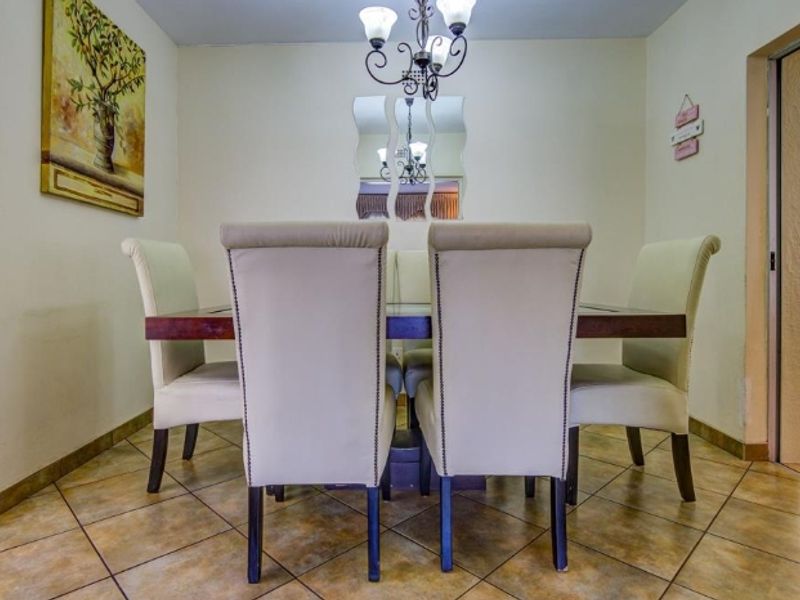 A dining room featuring ceramic tile flooring and a decorative chandelier, providing a functional space for meals.